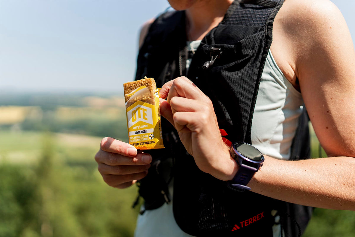 Person outdoors holding a sports bar packet with a scenic background