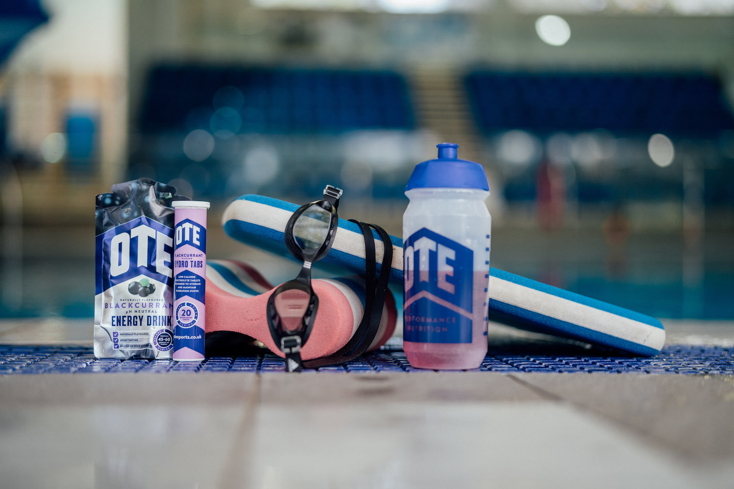 Selection of OTE Sports products placed around swimming goggles and floats.