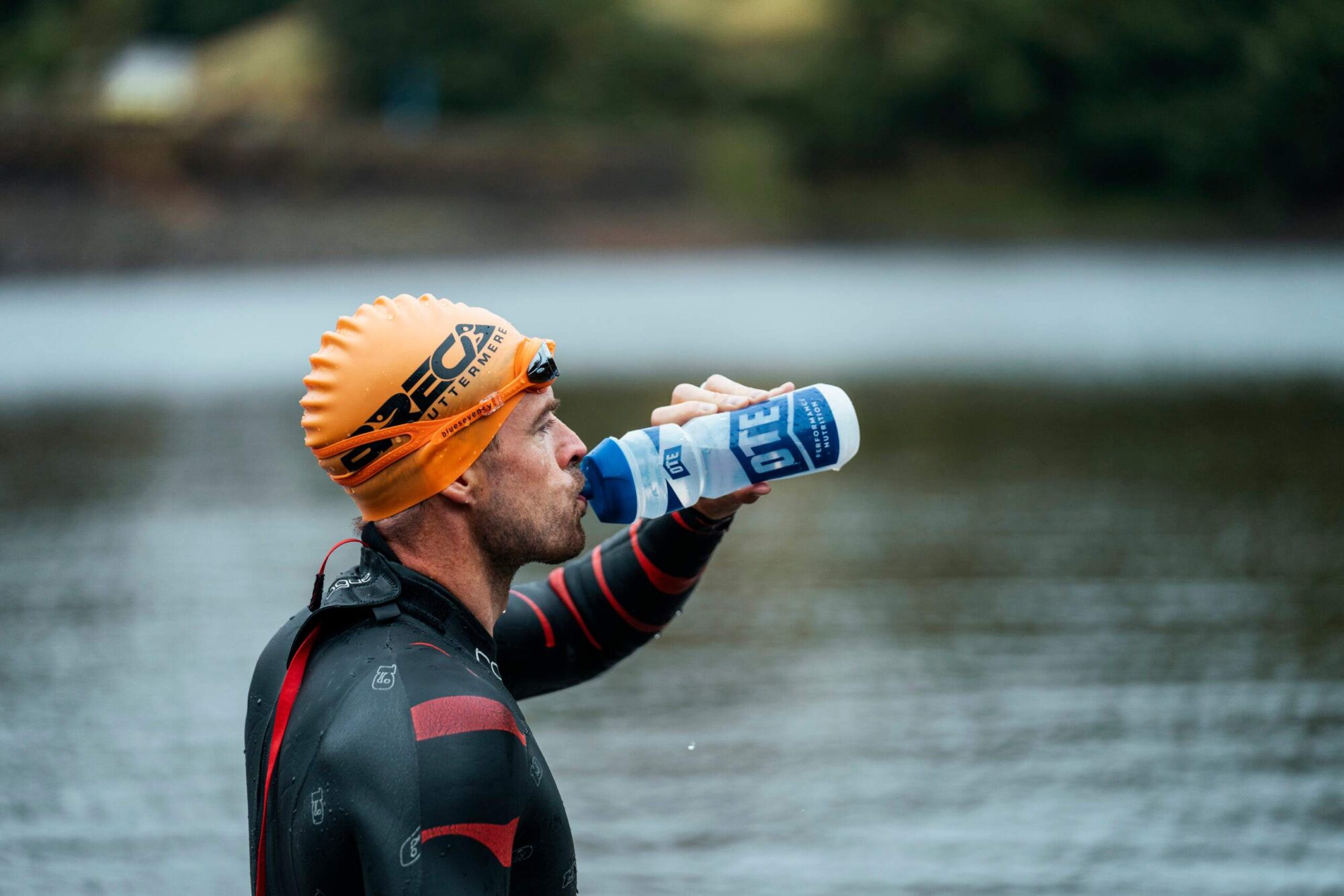 Triathlete drinking from an OTE Sports bottle.